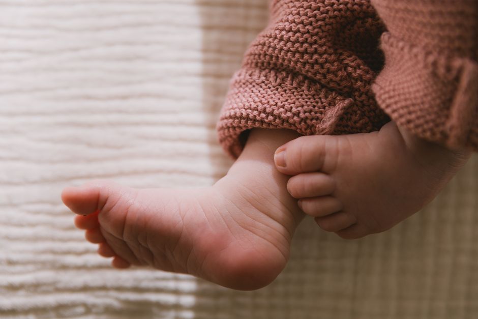 A warm close-up photo of a baby's foot in knitted clothing, evoking a cozy and tender mood