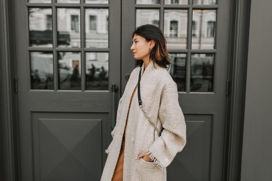 Asian woman posing stylishly in front of a modern gray door with casual elegance