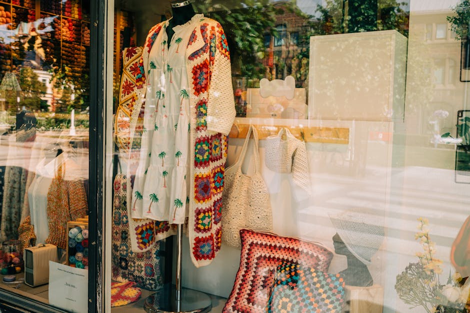 Window display of cozy knitted textiles and handmade clothing in a store.