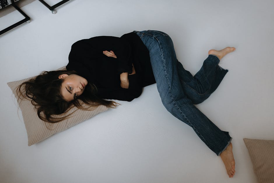 Fashion portrait of a young woman lying on the floor indoors dressed in casual clothing.