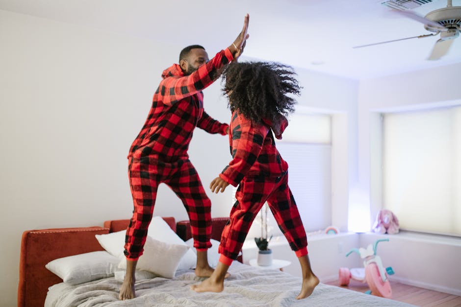 Playful father-daughter moment jumping on bed in matching pajamas, creating joyful memories.
