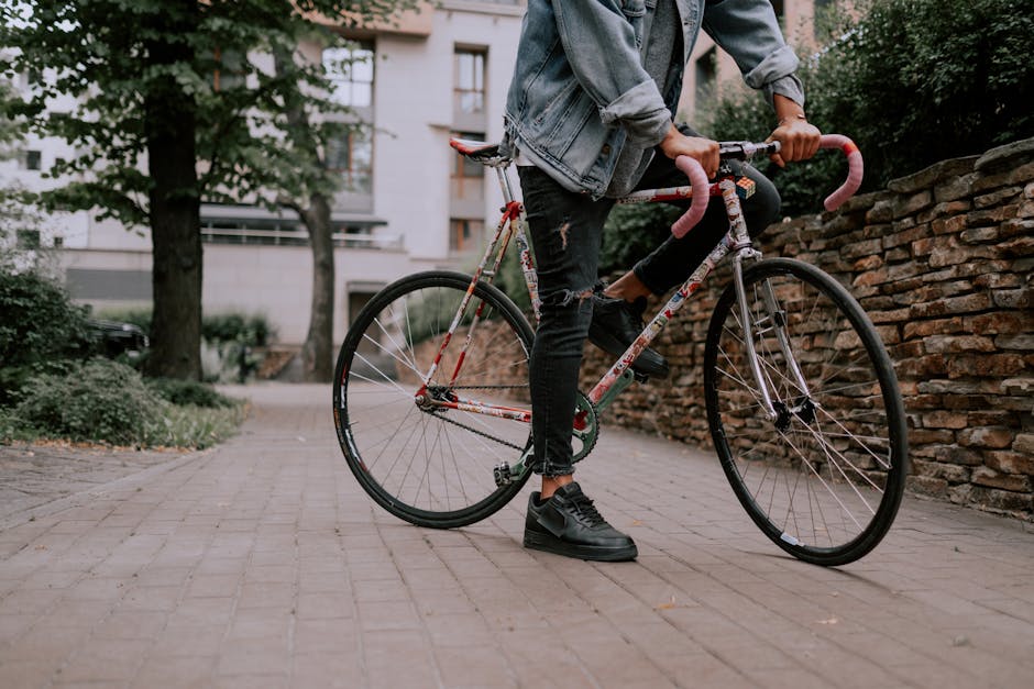 Person riding a decorated road bike on a pedestrian pathway in a city park setting.