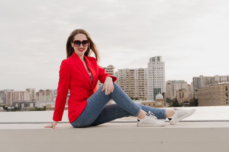 Stylish woman in red blazer posing against Baku skyline. Urban fashion and lifestyle.