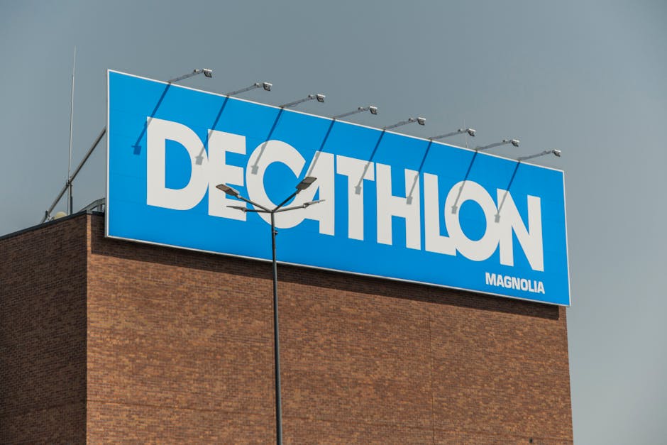 Close-up of a Decathlon store sign against a clear sky on a brick building.