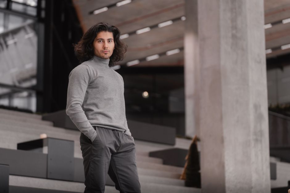 Stylish man in contemporary fashion poses in a modern Vienna building.