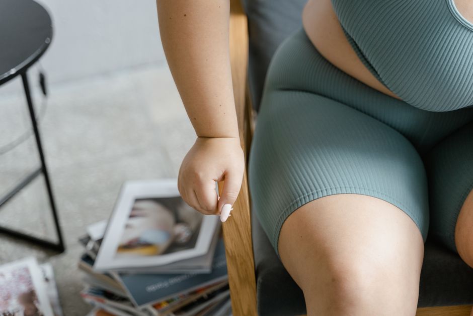 Close-up of a plus size woman in casual green outfit, sitting relaxed indoors.