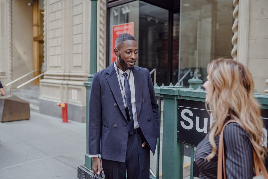 Businessman and woman talking in the city, near a subway entrance.