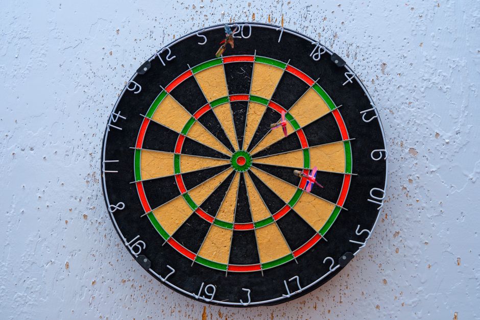 Vibrant dartboard against textured wall with darts on bullseye, symbolizing precision.