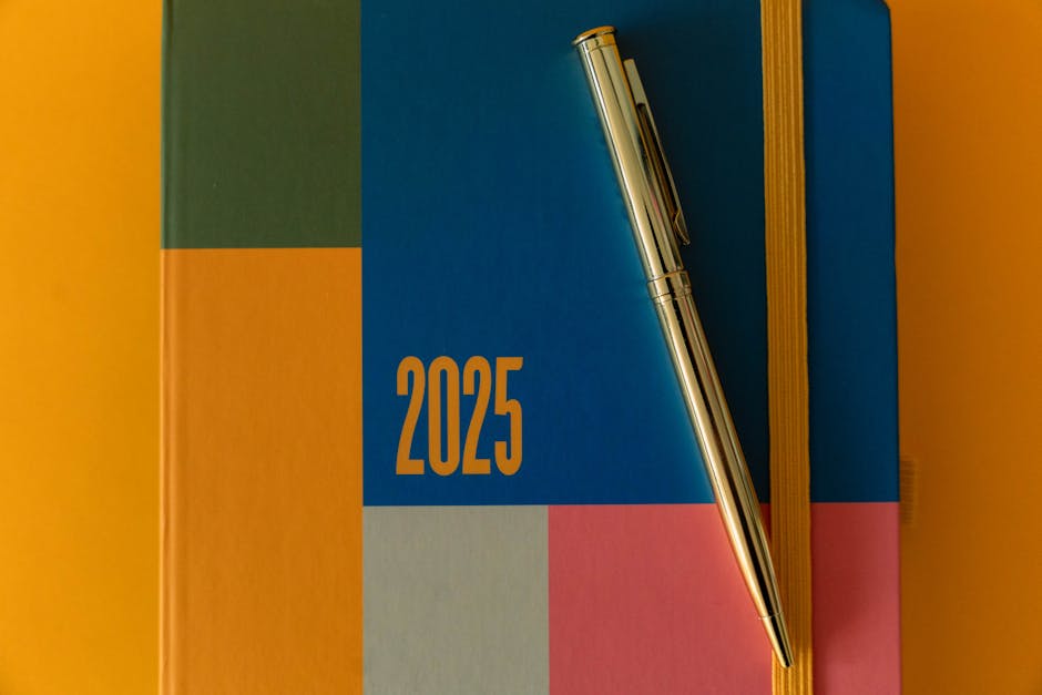 Modern 2025 planner with vibrant colors and a sleek silver pen on a flat lay design.
