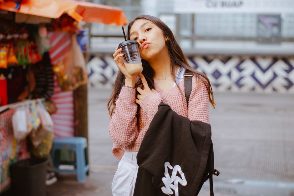 Young woman enjoying iced coffee on a vibrant street. Stylish and expressive.