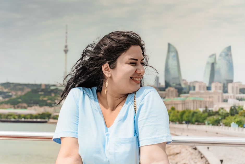Happy woman enjoying sunny day with iconic Flame Towers of Baku in the background.
